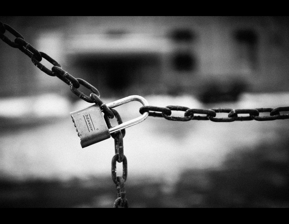 Black and white photograph of a chain secured with a padlock